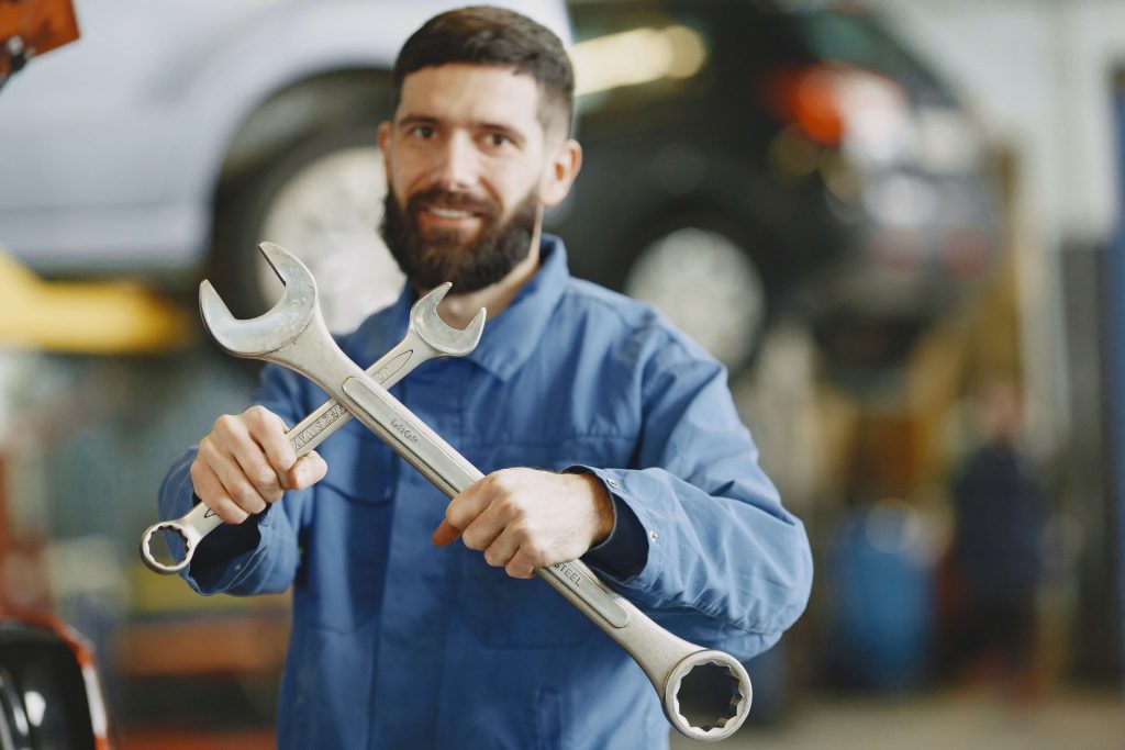 an expert in BMW Repair in Davie FL holds two wrenches