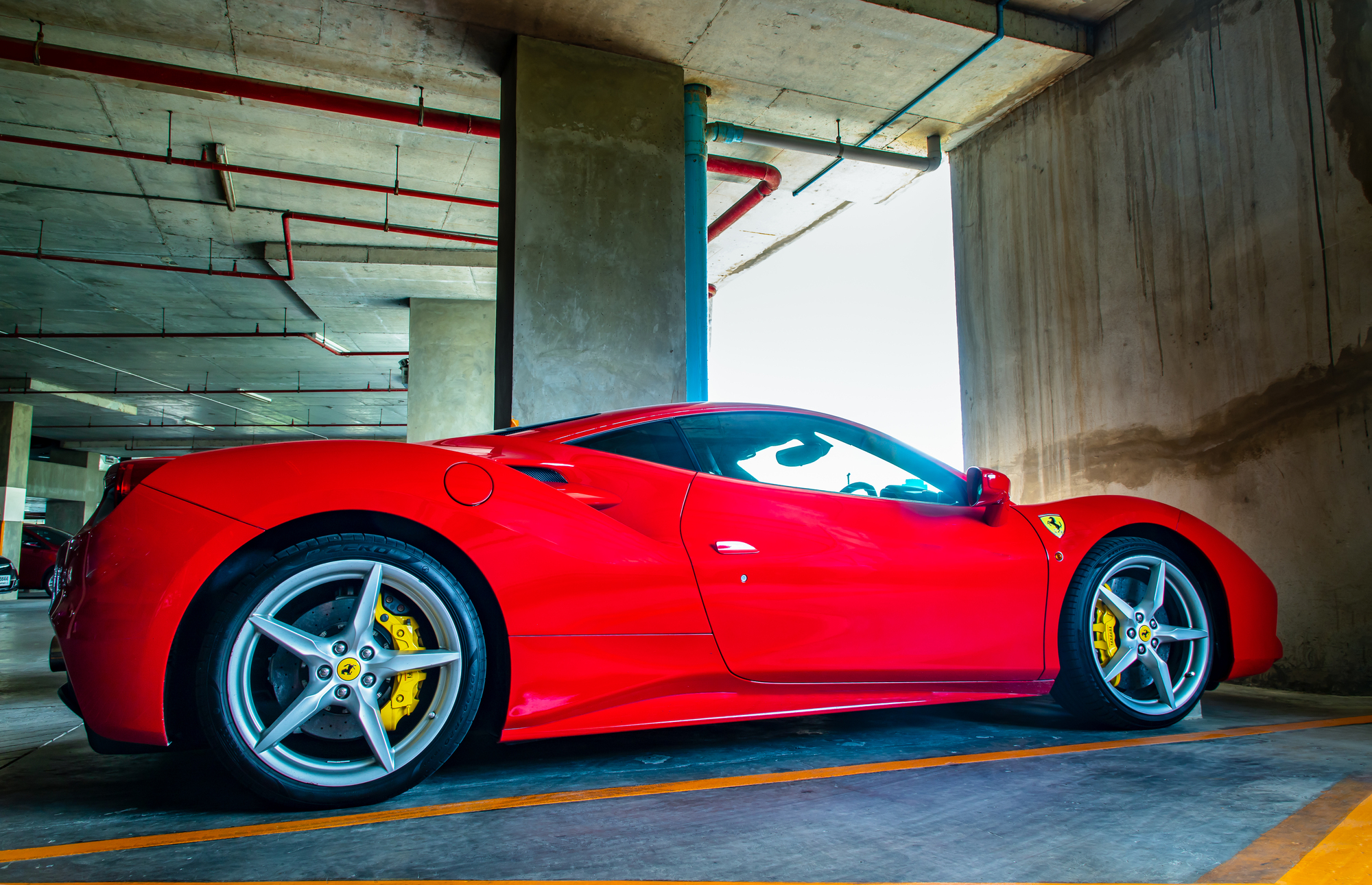 Side view of Red metallic Ferrari car in the parking lot.